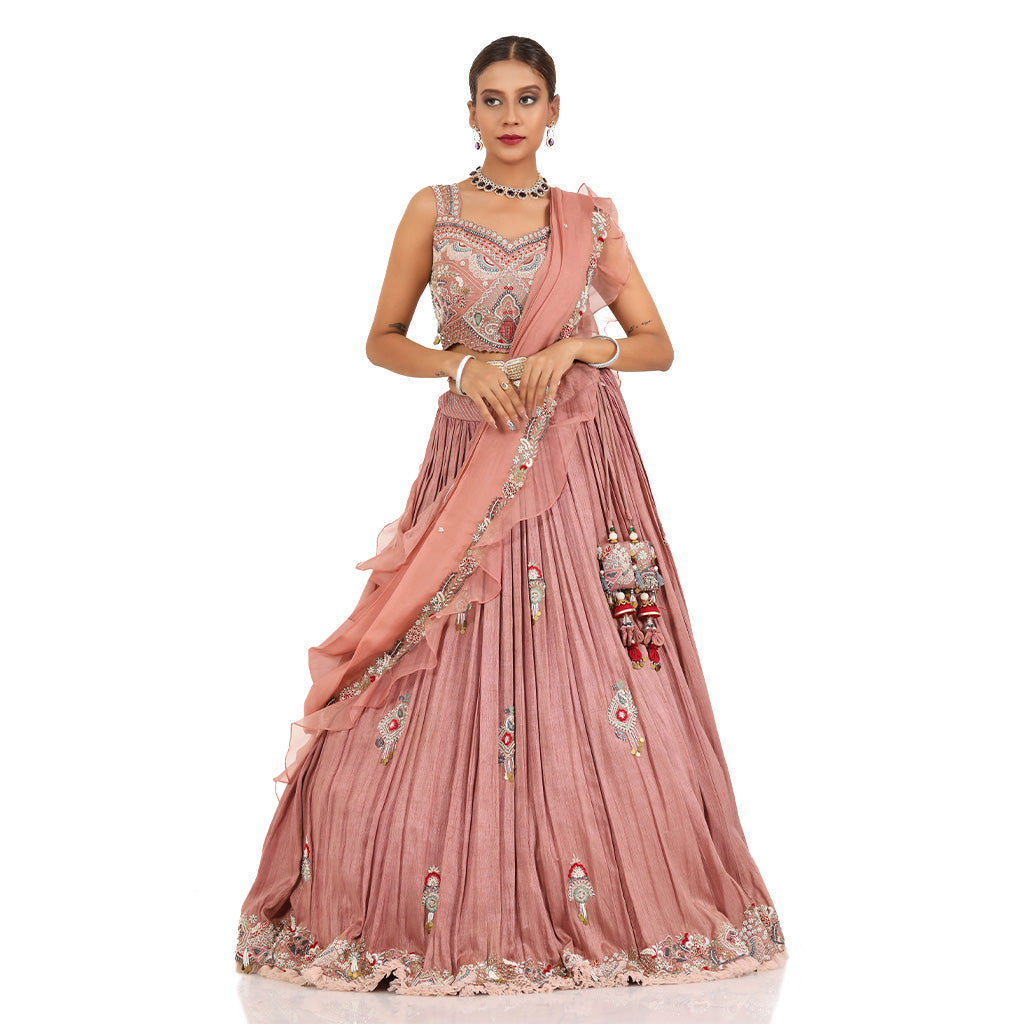A woman standing and wearing Rose Pink lehenga set attaining a bridal attire.