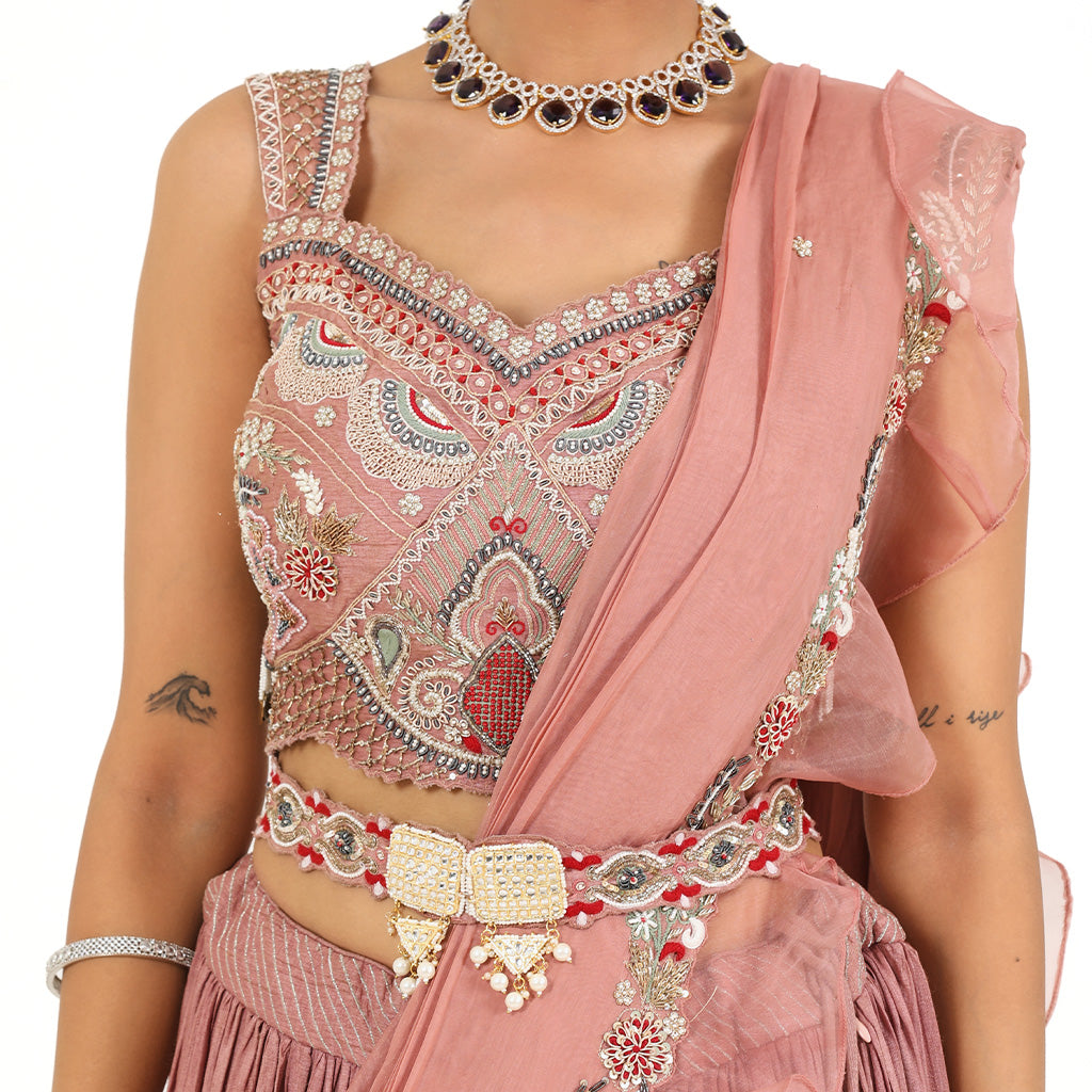 A woman standing and wearing Rose Pink lehenga set attaining a bridal attire.