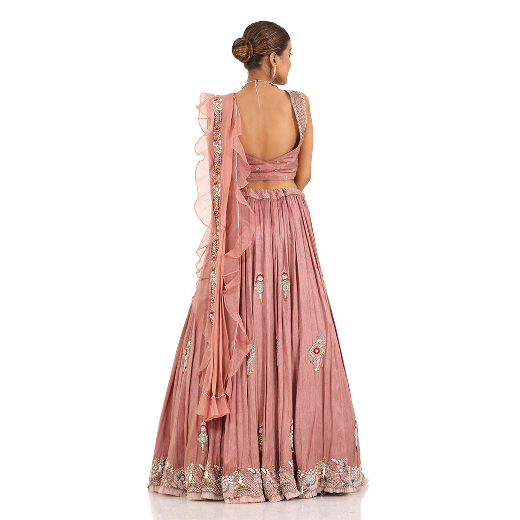 A woman standing and wearing Rose Pink lehenga set attaining a bridal attire.