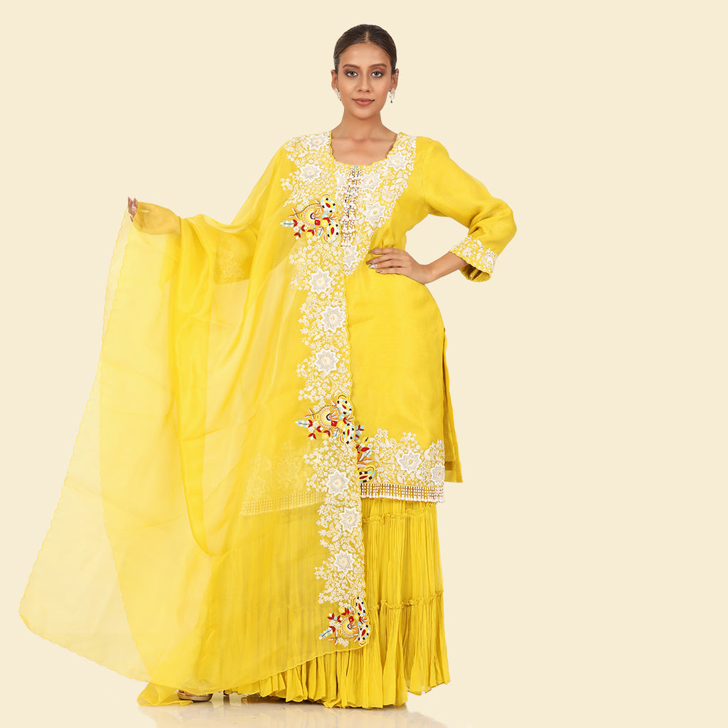 A woman standing and wearing Yellow Pearl Sharara Set.