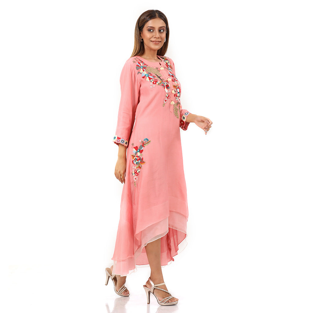 A woman standing and wearing Peach Floral Embroidery High Low Tunic.