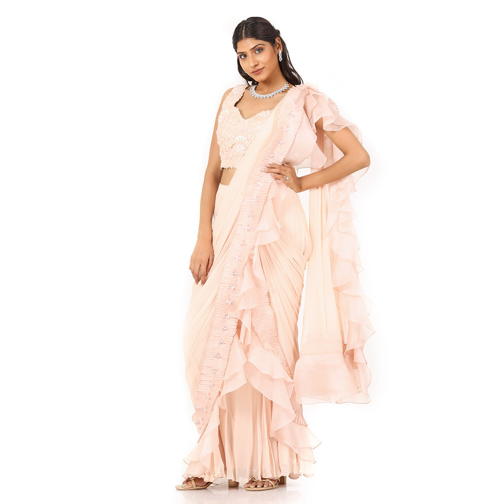 A woman standing and wearing Peach Colored Drape Saree.