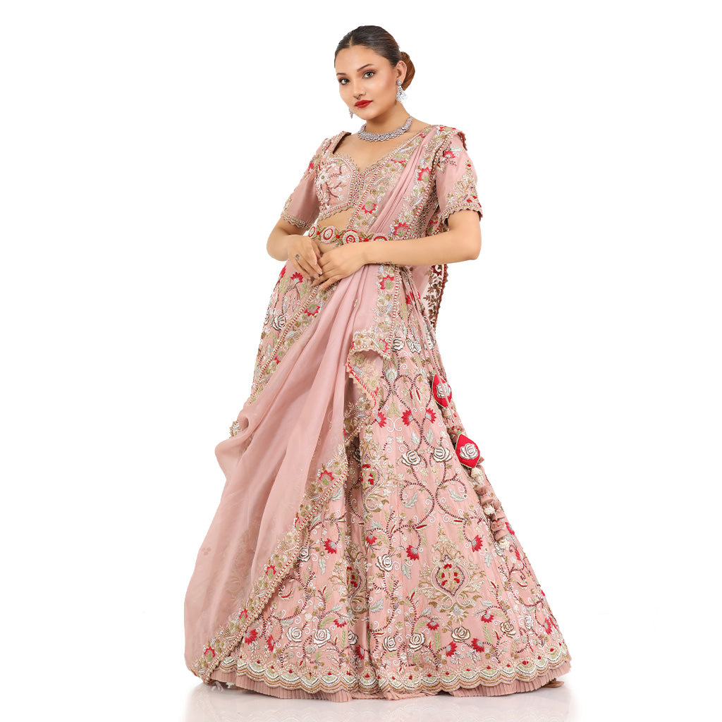 A woman standing and wearing Blush Pink Colored Rose Flower Lehenga Set.