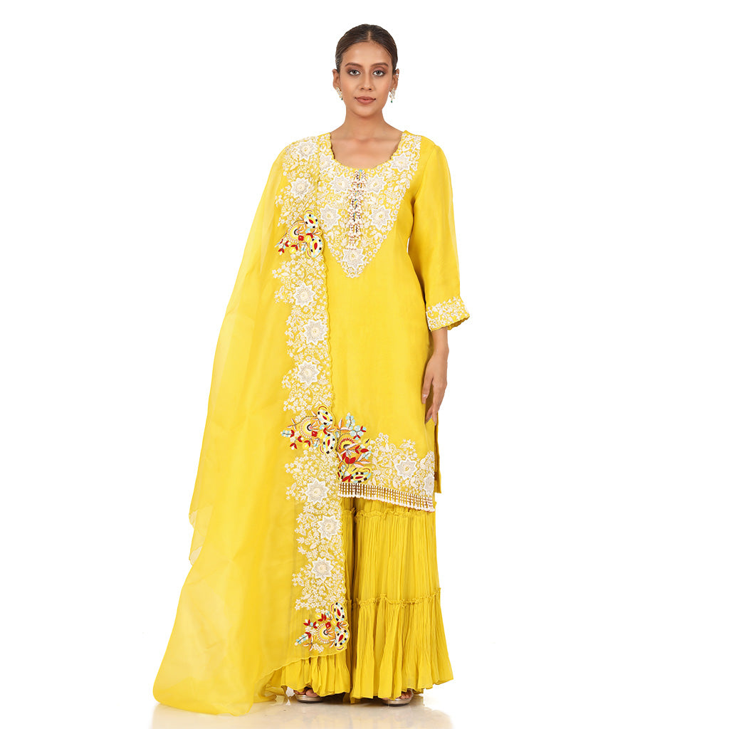  A woman standing and wearing Yellow Pearl Sharara Set.