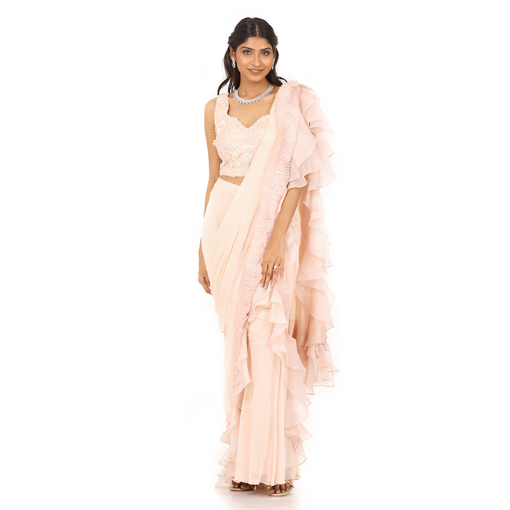 A woman standing and wearing Peach Colored Drape Saree.