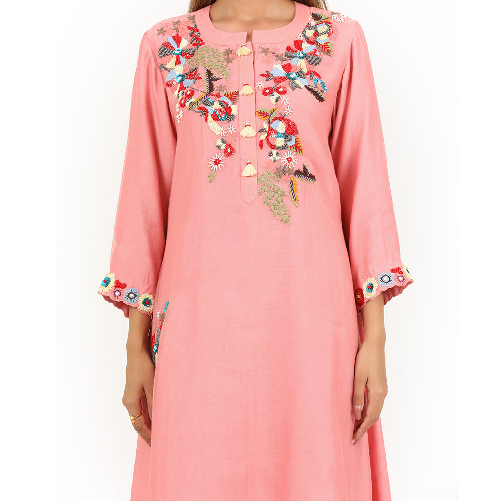 A woman standing and wearing Peach Floral Embroidery High Low Tunic.