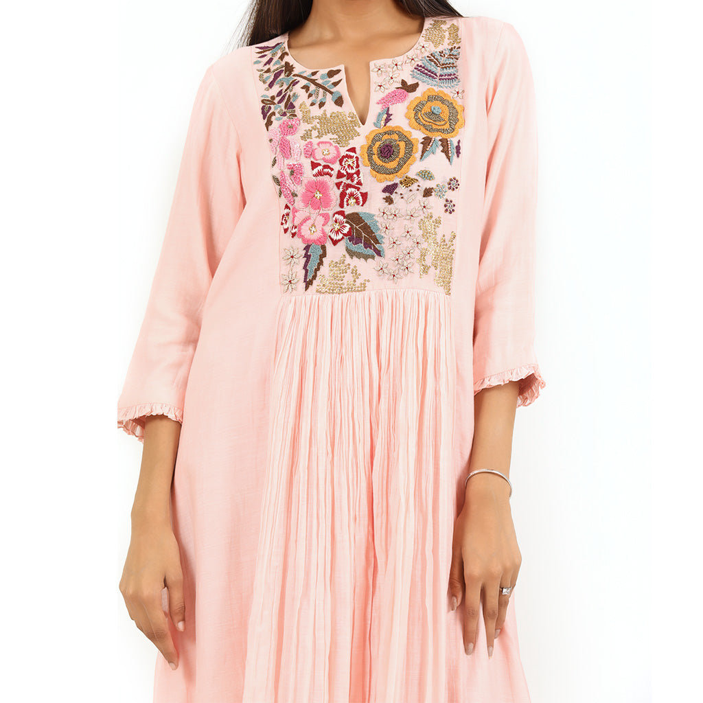 A woman standing and wearing Pink Gathered Floral Yoke Tunic.