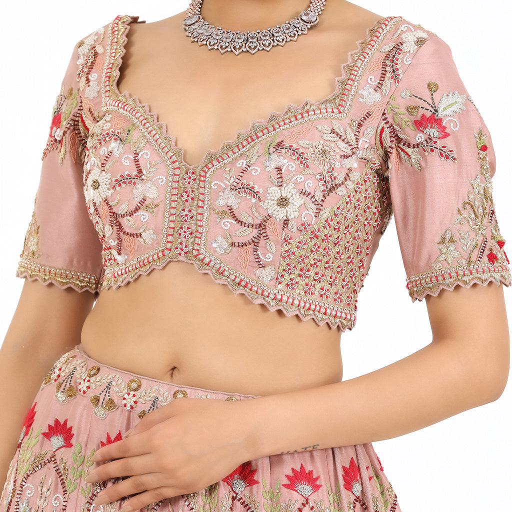 A woman standing and wearing Blush Pink Colored Rose Flower Lehenga Set.