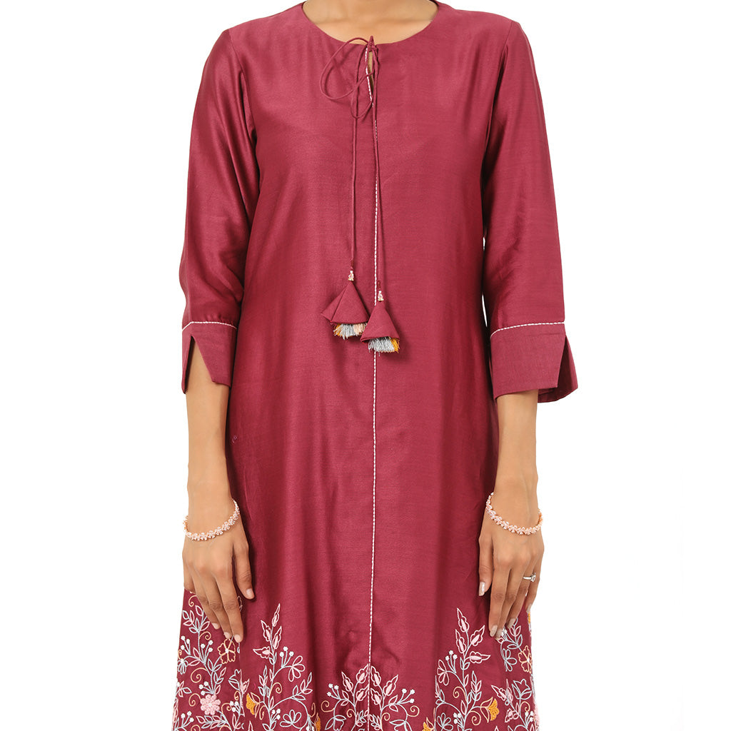 A woman standing and wearing pink colored Floral French Knot Kurta Set.