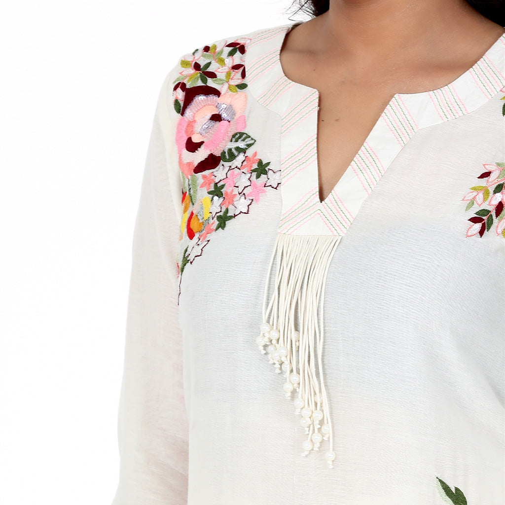 A woman standing and wearing white colored Ivory Floral Placement Kurta Set.