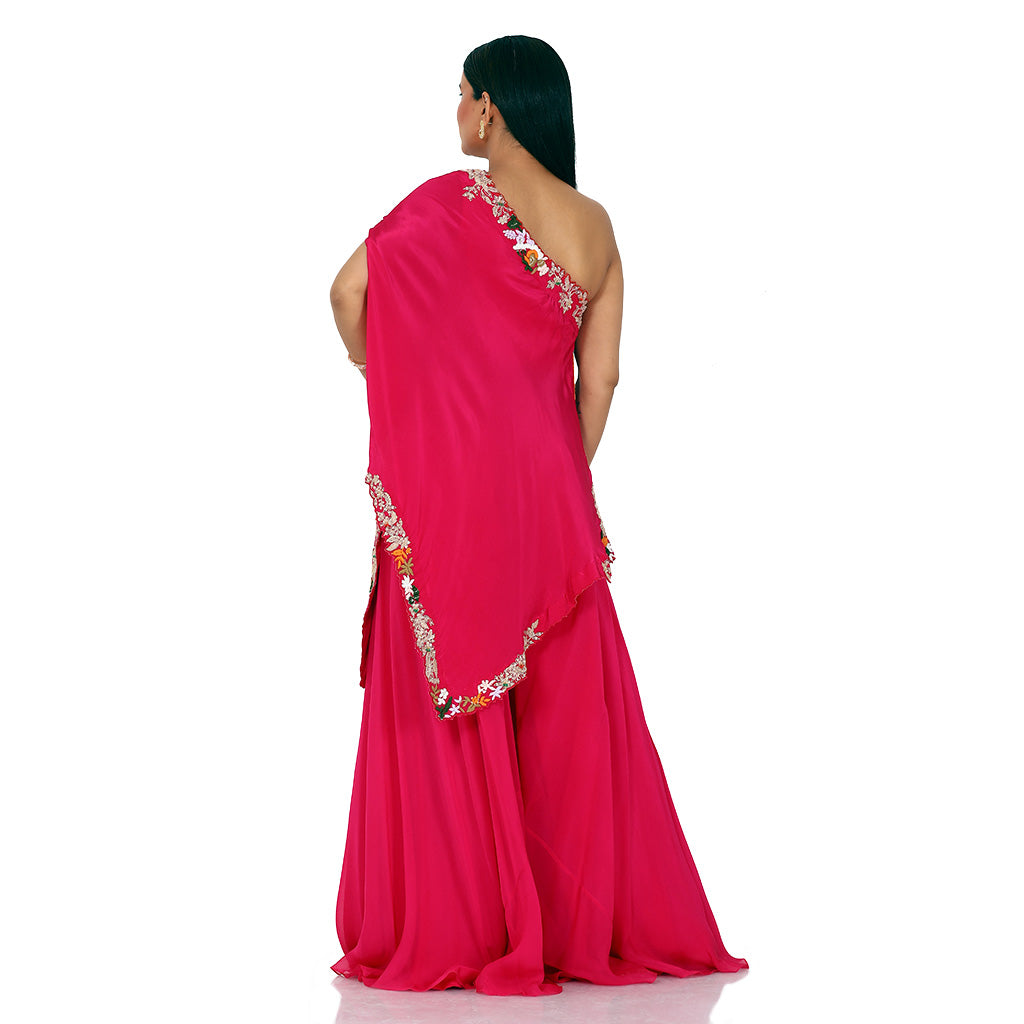 A woman standing and wearing Red Colored Coral Red One Shoulder Cape.