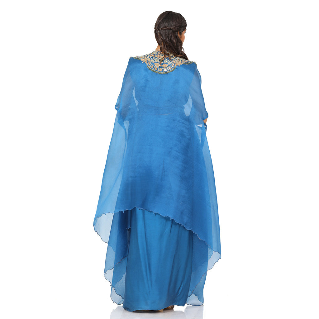 A woman standing and wearing Blue Colored Asymmetrical Cape.