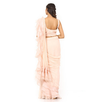 A woman standing and wearing Peach Colored Drape Saree.