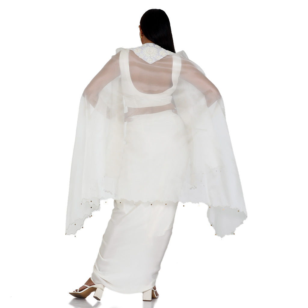 A woman standing and wearing Ivory Colored 3D Cape Dress.