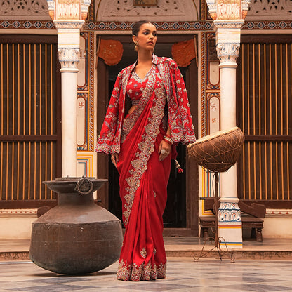 A woman standing and wearing Red Colored Jacket Saree.