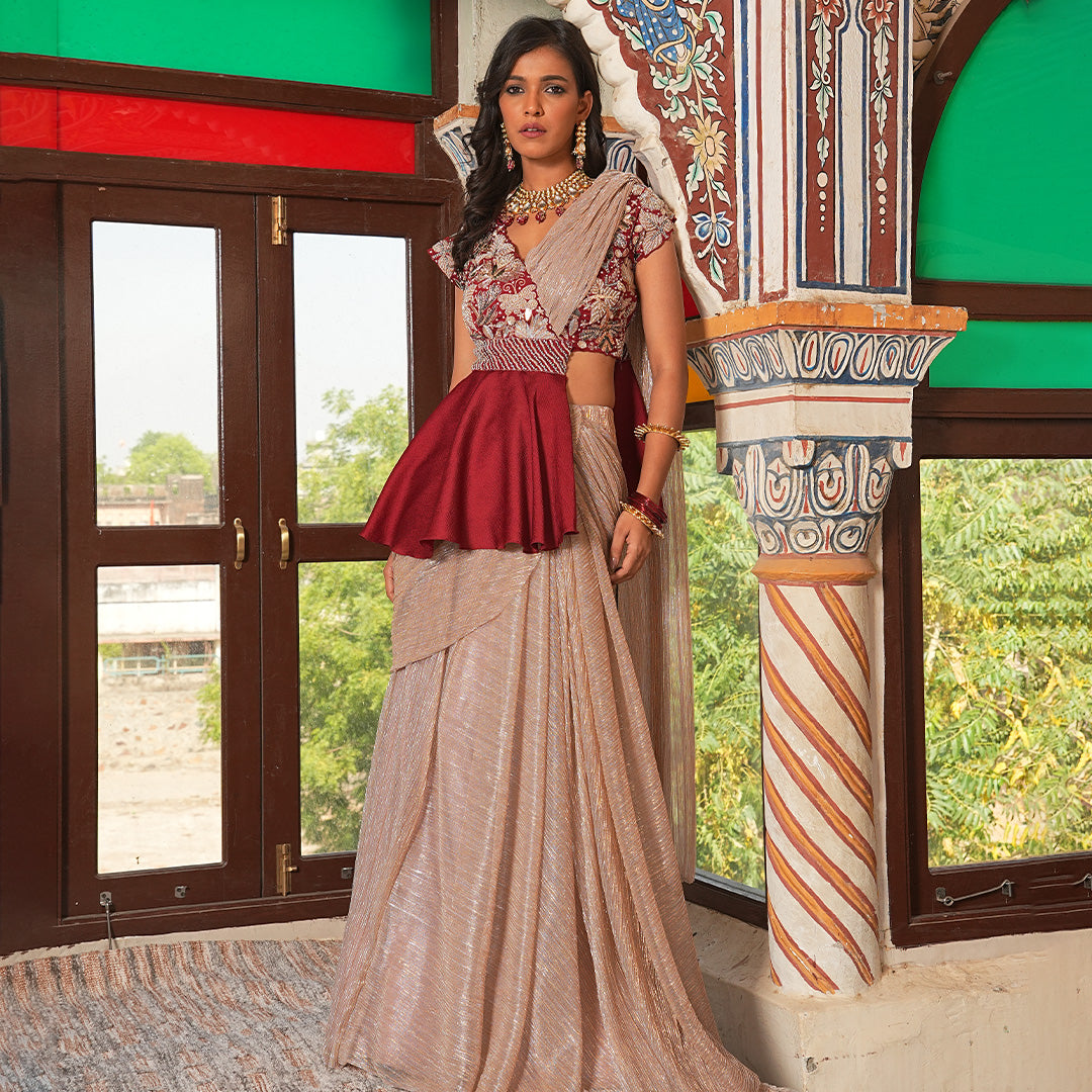 A woman standing and wearing Maroon Colored Peplum Saree.