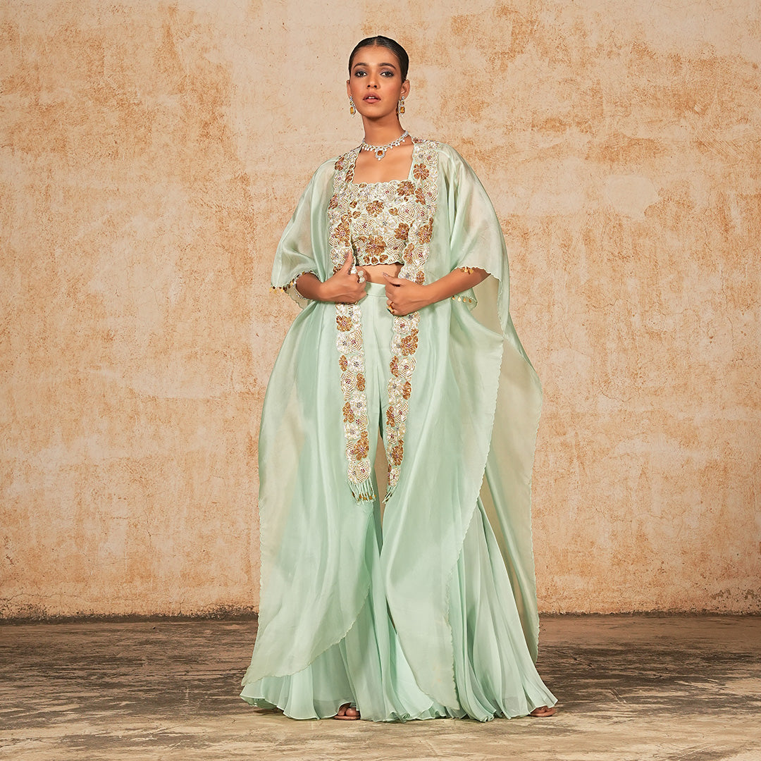 A woman standing and wearing Green Floral Cape Dress.