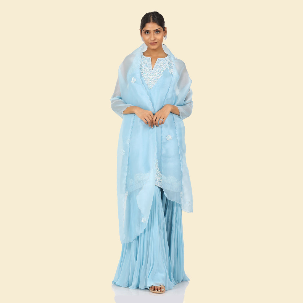 A woman standing and wearing Blue Halter Kurta Sharara Set.