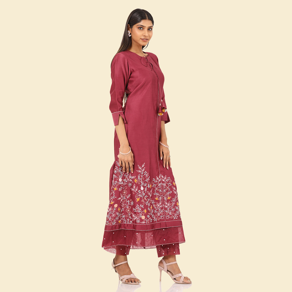 A woman standing and wearing pink colored Floral French Knot Kurta Set.