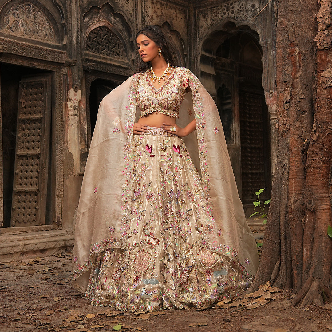 A woman standing and wearing Gold Self Tissue Lehenga Set.