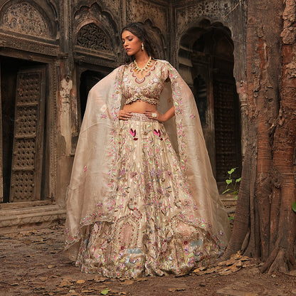 A woman standing and wearing Gold Self Tissue Lehenga Set.