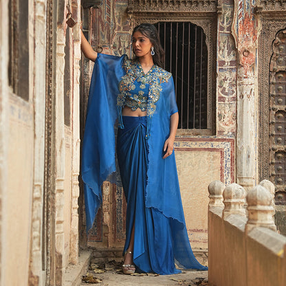 A woman standing and wearing Blue Colored Asymmetrical Cape.